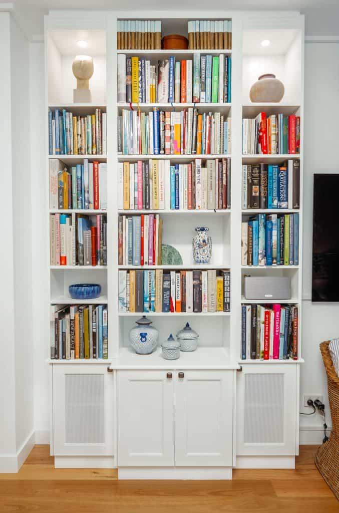 Floor-to-ceiling bookcase in a New Farm, Brisbane home displaying an eclectic mix of books, pottery, and decorative pieces, highlighting the homeowner's personal style in a bright and cozy living space.