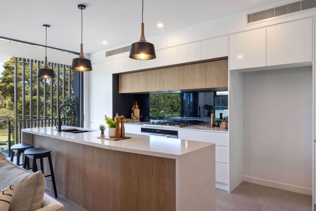 Contemporary kitchen design featuring pendant lighting, a black sink with a high faucet, and a wooden breakfast bar with stylish black stools.