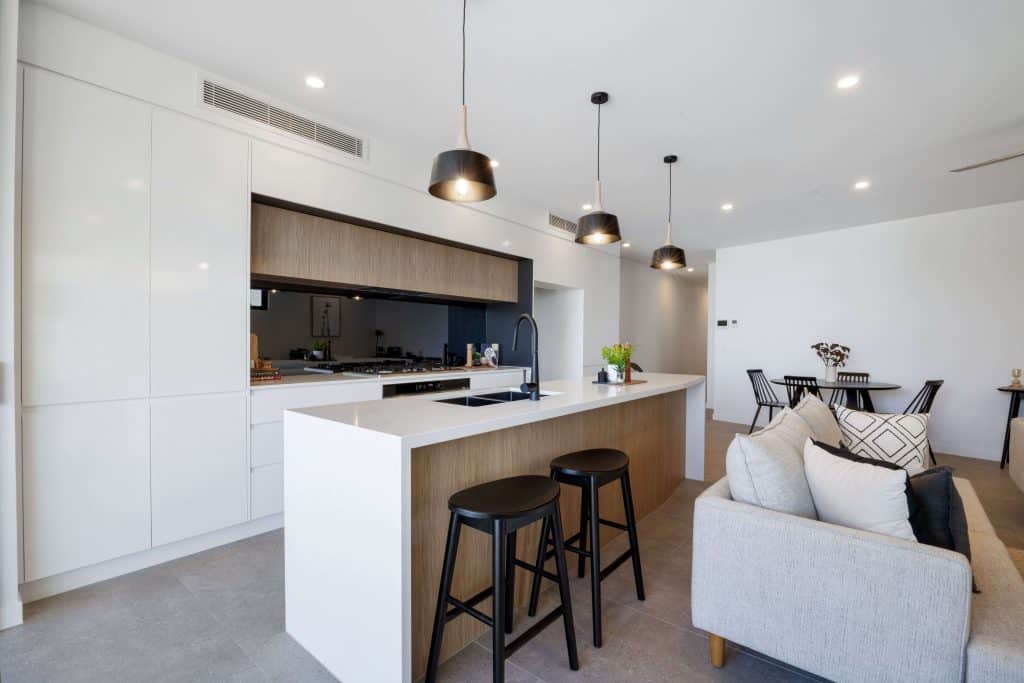 Spacious and well-lit kitchen area with modern appliances, white cabinetry, and a minimalist dining setup, seamlessly blending with the open living space.