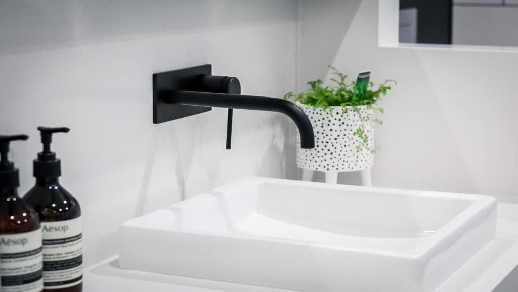 Close-up of a modern white sink featuring a black tap